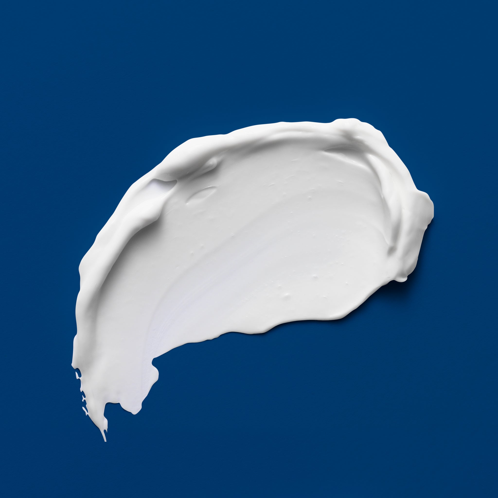 A smear of bright white cream on a dark blue background