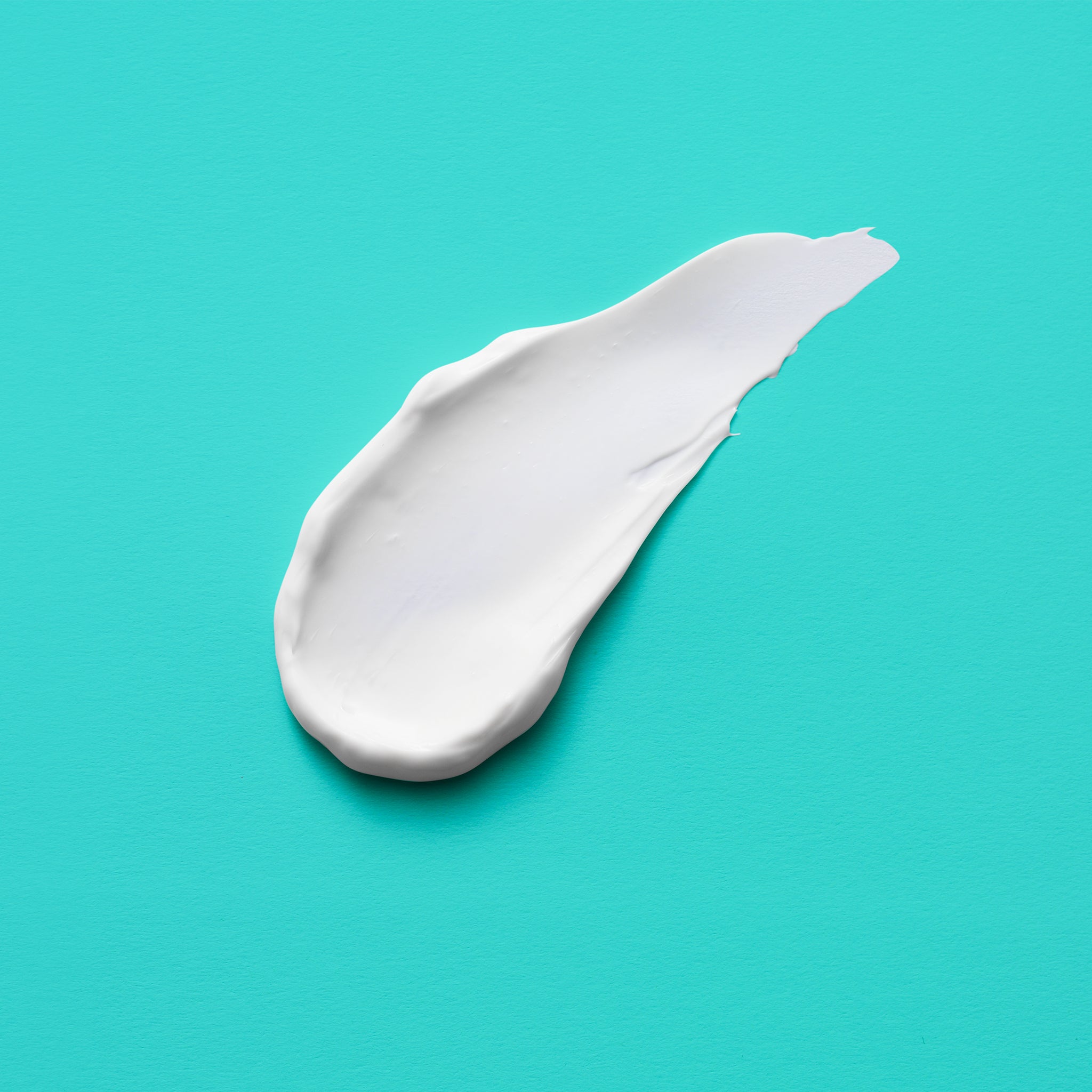 A smear of bright white cream on a aqua green background