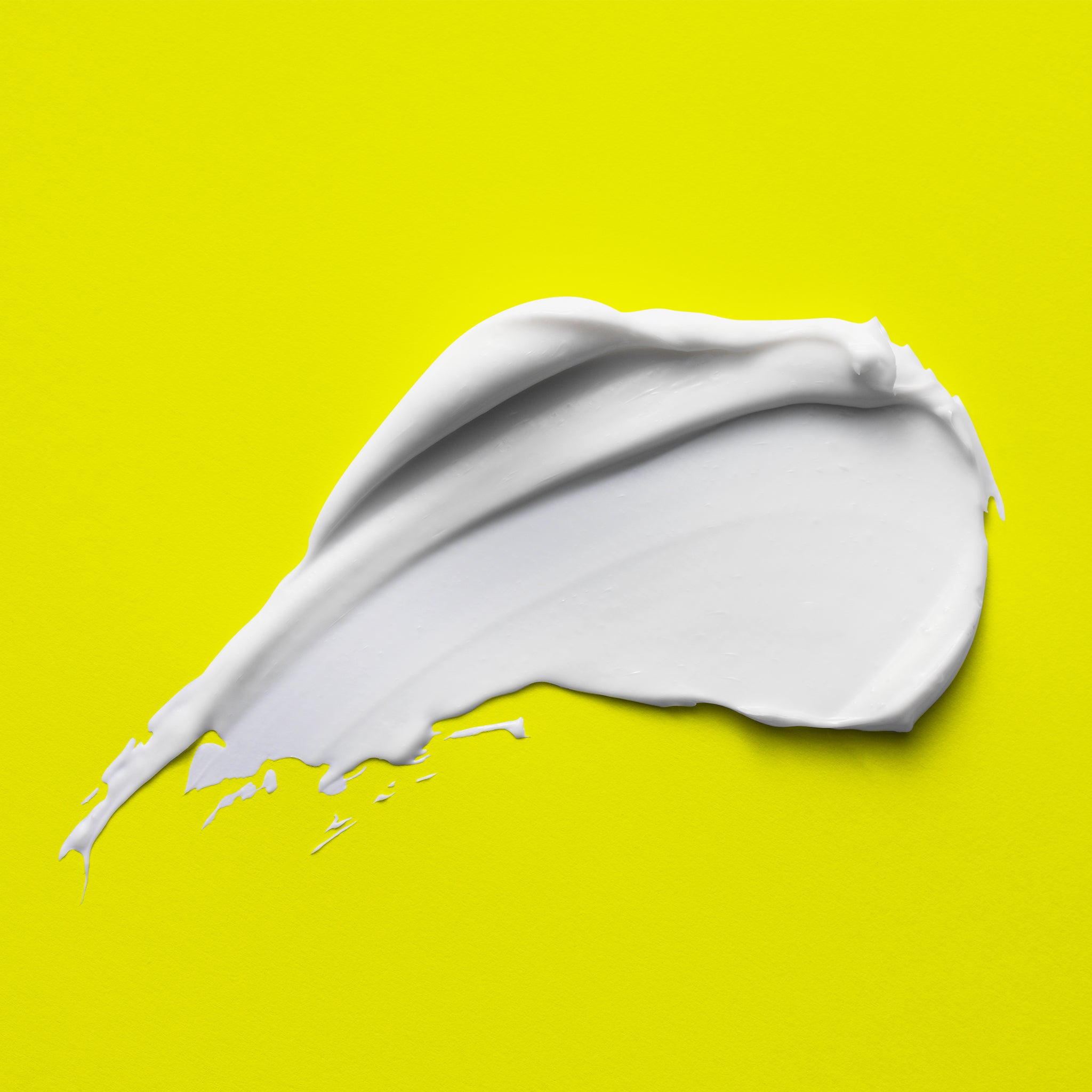A smear of bright white cream on a bright yellow background