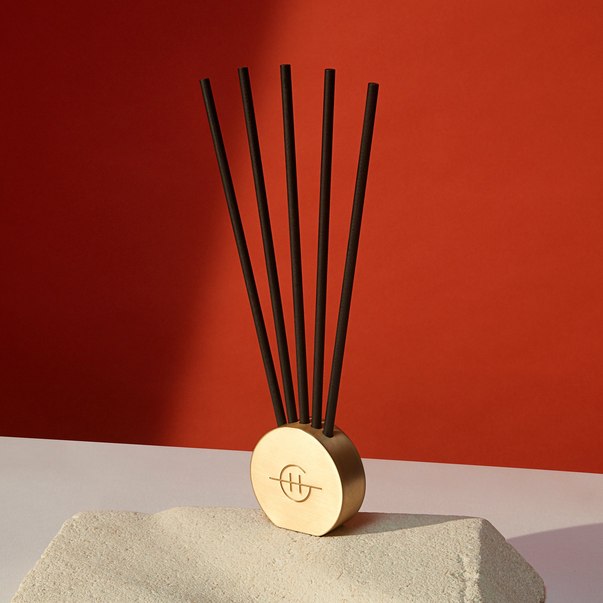 Glasshouse Fragrances Scent Stems™ in vessel on tabletop with red background